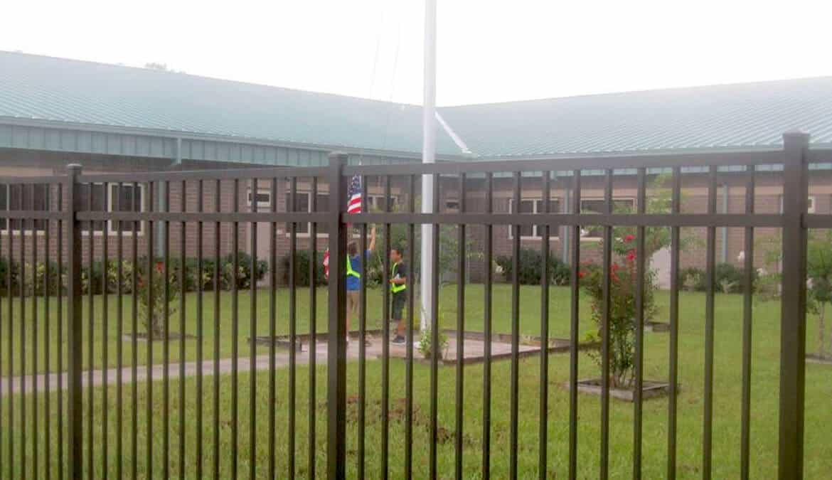 Isaac Davis and Nate Helmath lower the flag in the rain at Coppergate Elementary School, Middleberg, Florida